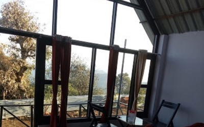 Interior of a cottage showing floor-to-ceiling windows and outdoor balcony