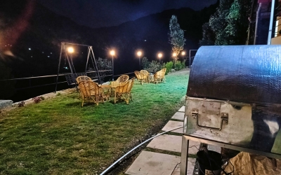 Outdoor lawn seating area with a barbecue grill and string lights at night