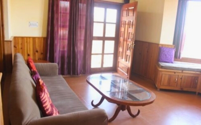 Living area with a sofa, coffee table, and large window leading to a balcony