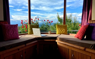 Cozy window seating area with pillows overlooking a panoramic mountain and rose garden view